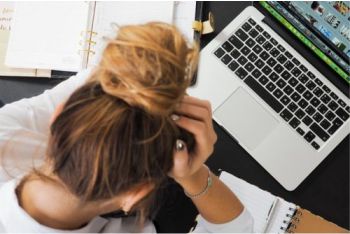 Woman with her head in her hands in front of a computer
