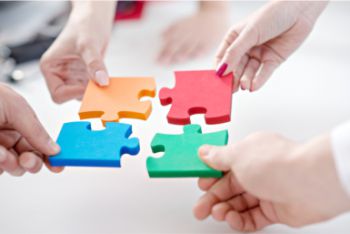 People holding separate pieces of a jigsaw and bringing them together