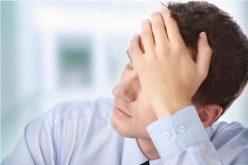 Man in a blue shirt, hand on his forehead looking stressed